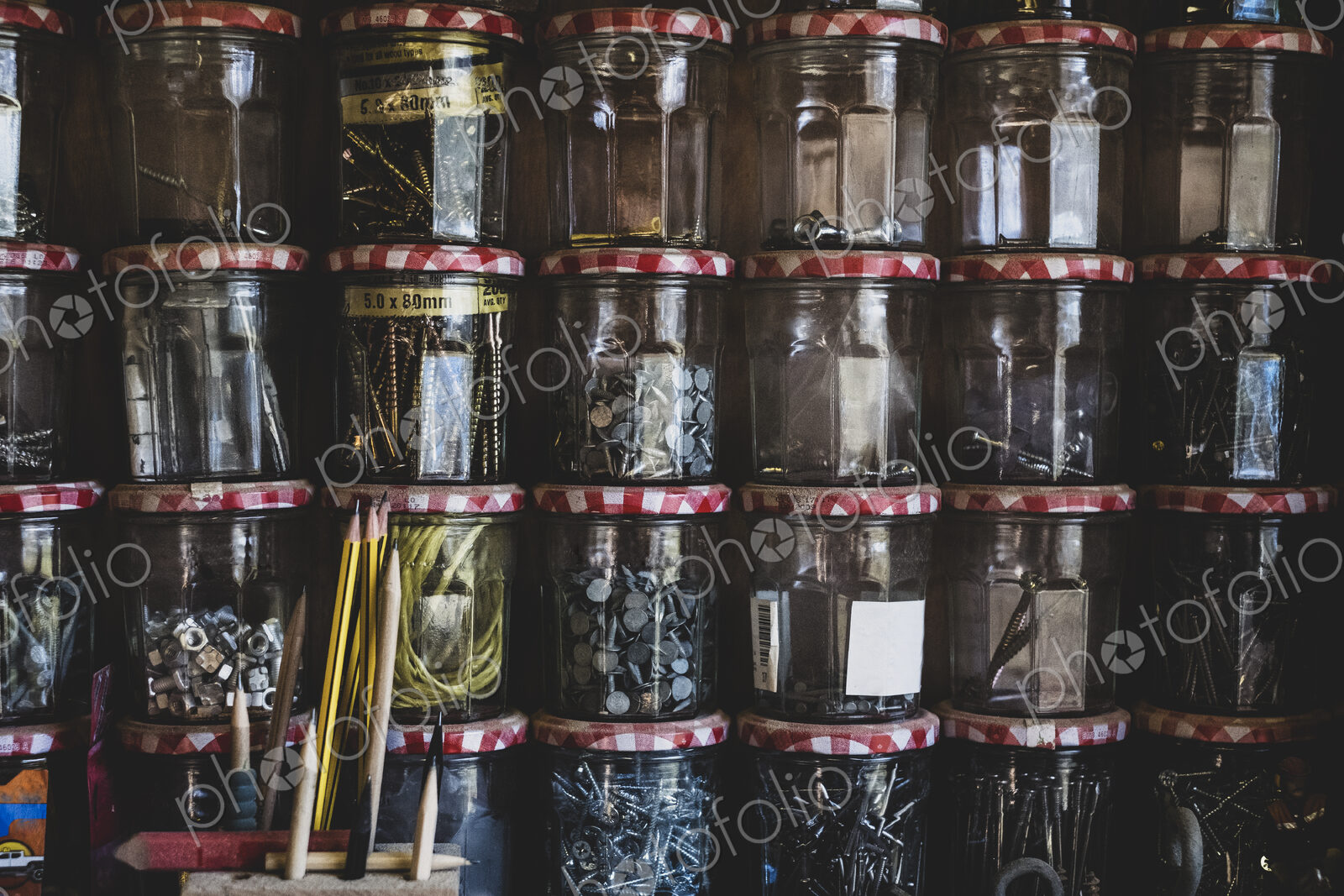 Close up of stack of jam jars containing selection of nail and screws.