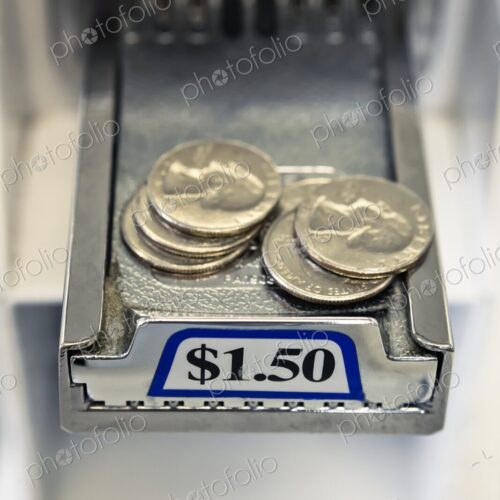 Close-up of stacks of United States coins, quarters on the sliding payment tray of a…