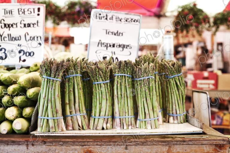 Close up of stacks of fresh green asparagus at a fruit and vegetable market.