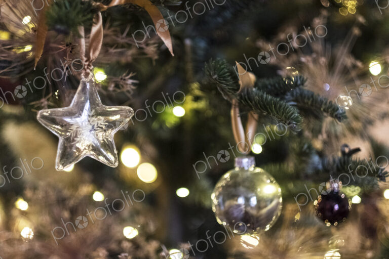 Close up of star shaped glass ornament and bauble on Christmas Tree.