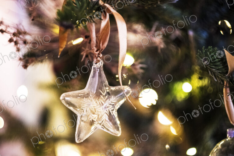 Close up of star shaped glass ornament on Christmas Tree.