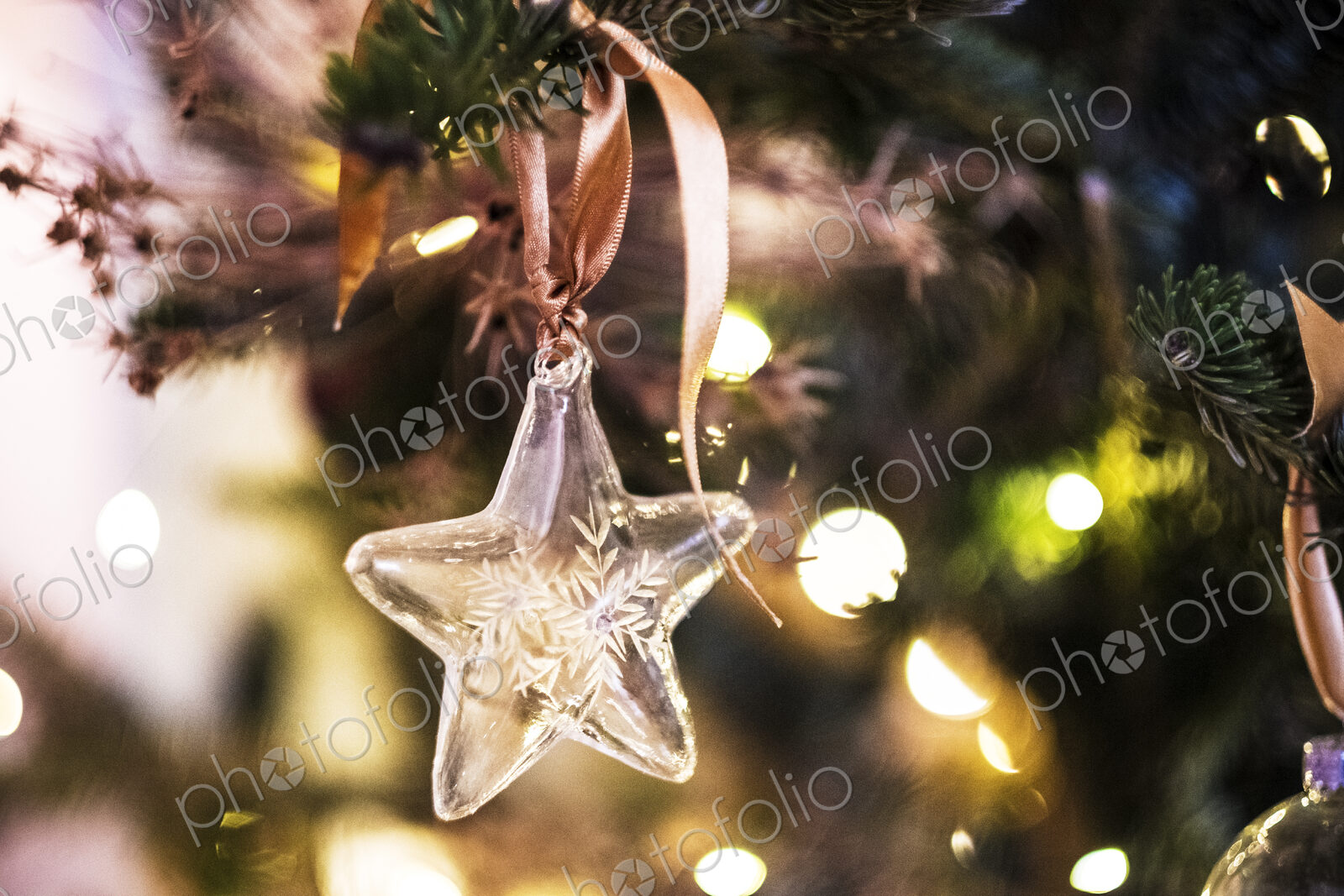 Close up of star shaped glass ornament on Christmas Tree.