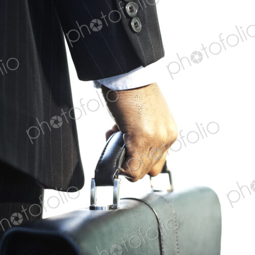 Close-up of the hand of a black businessman holding a brief case. Close-up of the hand of a black businessman holding a brief case.