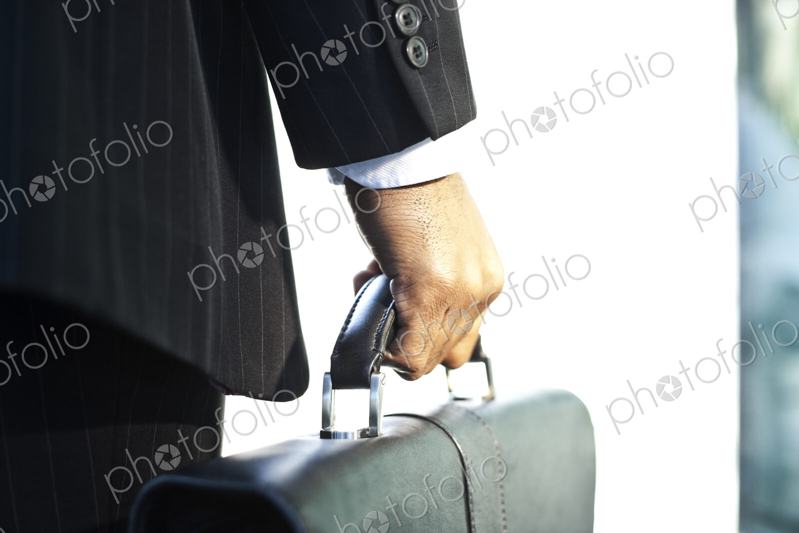 Close-up of the hand of a black businessman holding a brief case.