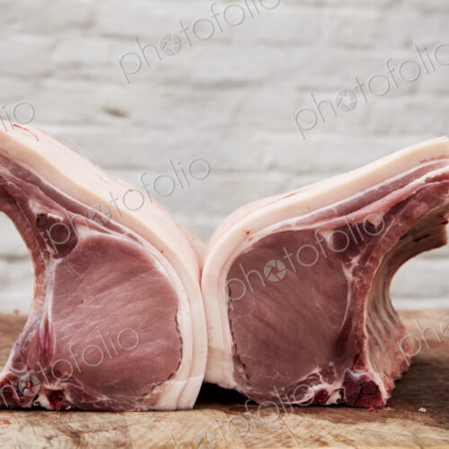Close up of two pieces of pork loin on a wooden butcher's block.