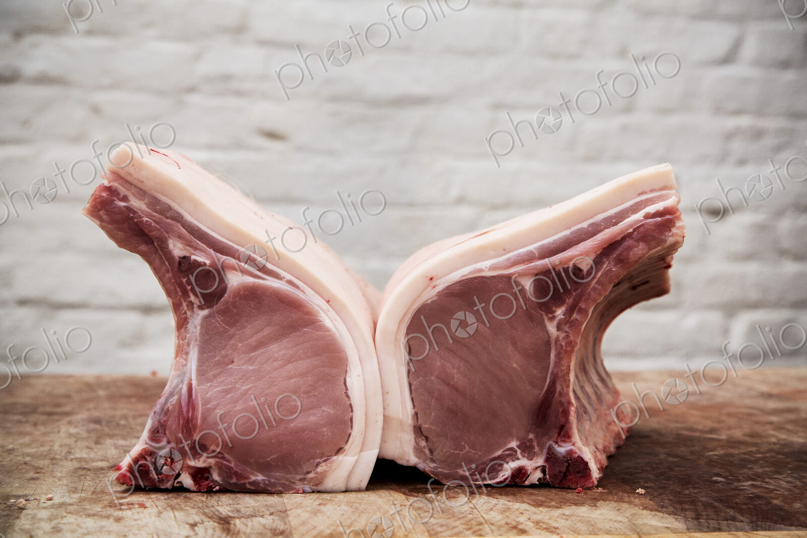 Close up of two pieces of pork loin on a wooden butcher’s block.