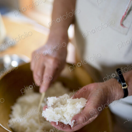 Close up of woman standing at a table in a kitchen, making sushi. Close up of woman standing at a table in a kitchen, making sushi.