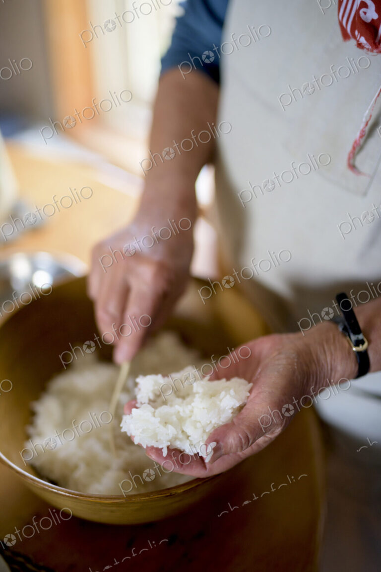 Close up of woman standing at a table in a kitchen, making sushi.