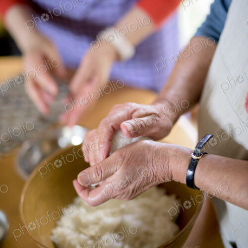 Close up of woman standing at a table in a kitchen, making sushi. Close up of woman standing at a table in a kitchen, making sushi.