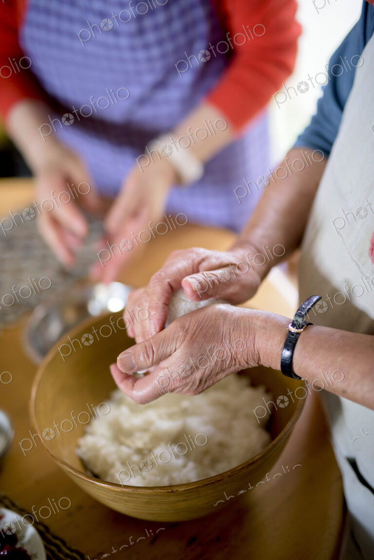 Close up of woman standing at a table in a kitchen, making sushi.