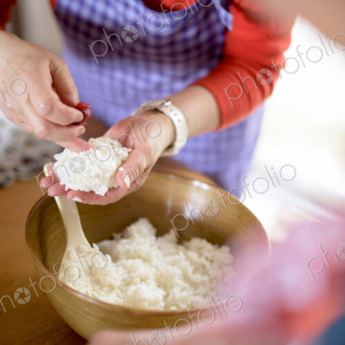 Close up of woman standing at a table in a kitchen, making sushi. Close up of woman standing at a table in a kitchen, making sushi.