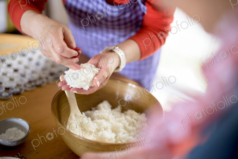 Close up of woman standing at a table in a kitchen, making sushi.