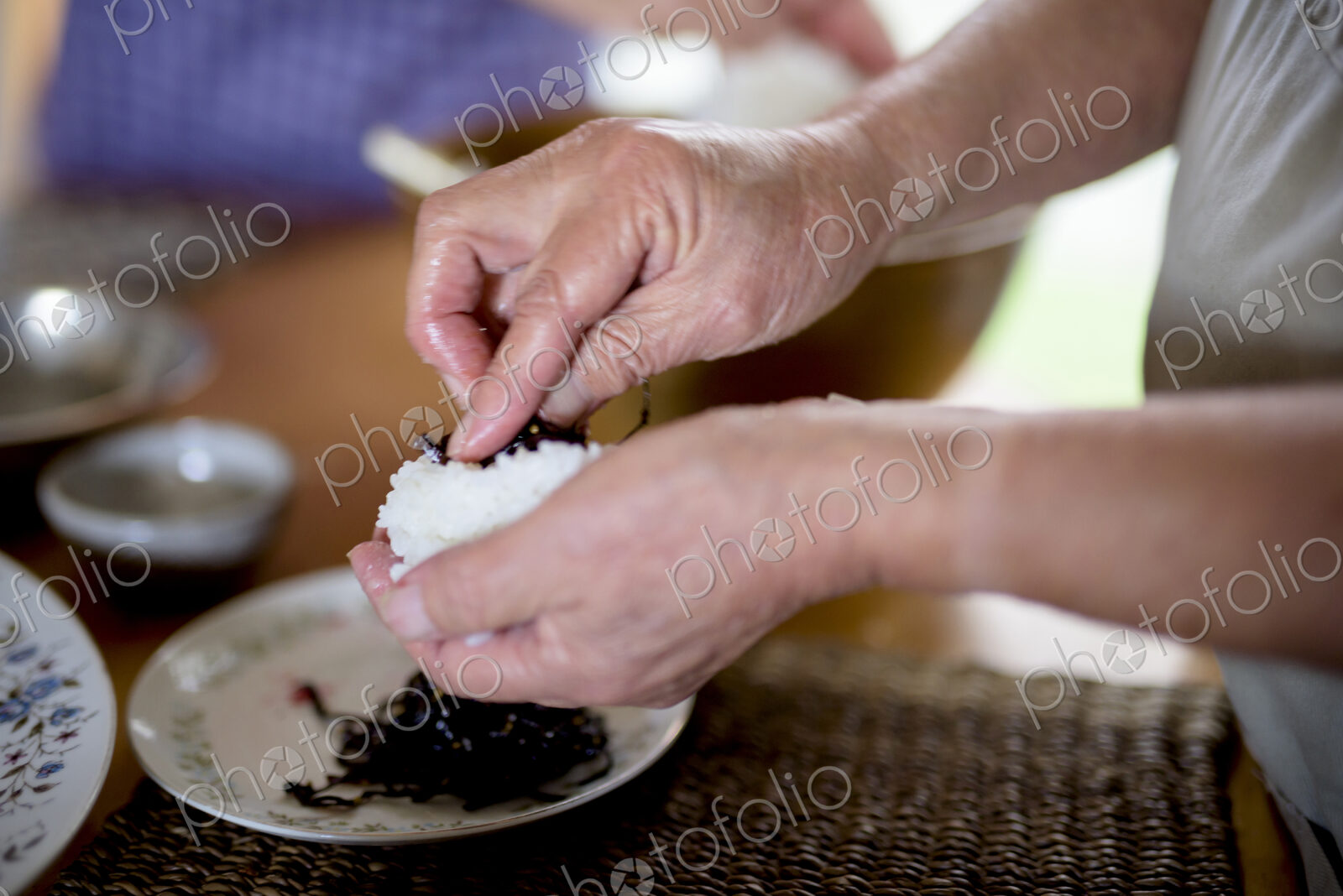Close up of woman standing at a table in a kitchen, making sushi.