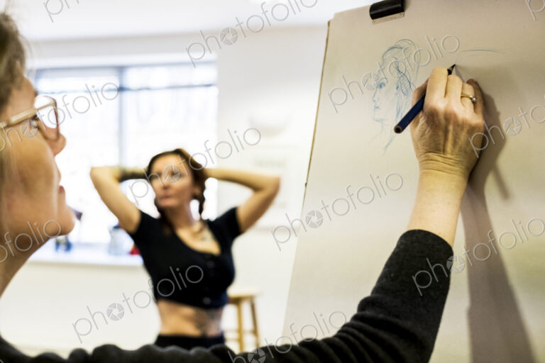 Close up of woman standing at easel at a life drawing class drawing a model