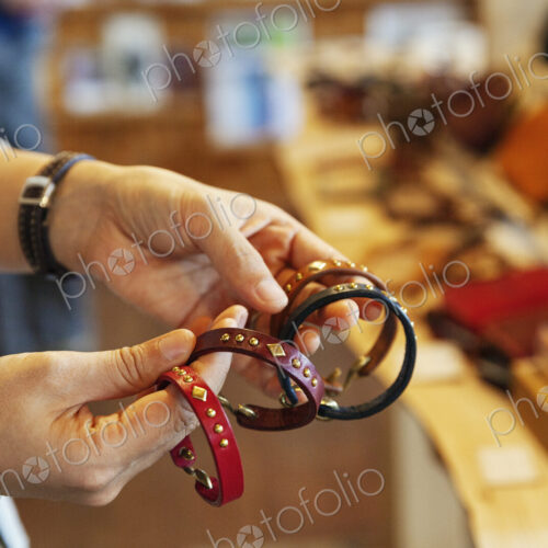 Close up of woman standing in a leather shop, holding leather bracelets. Close up of woman standing in a leather shop, holding leather bracelets.
