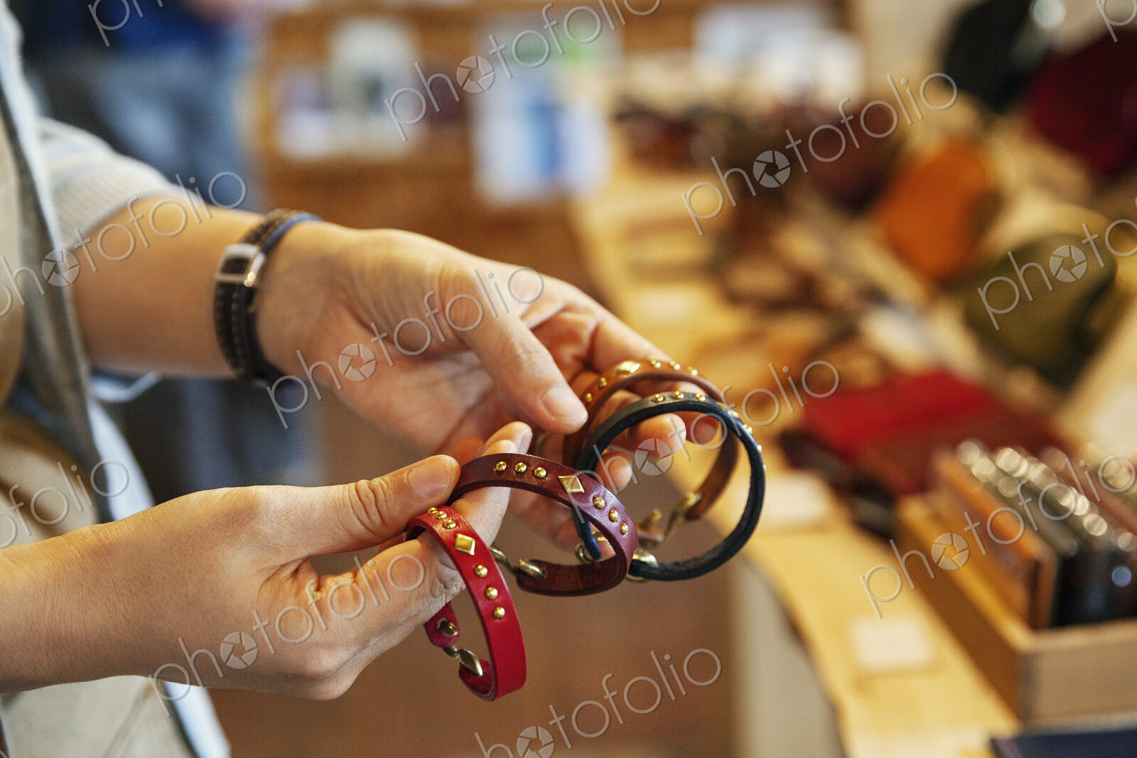 Close up of woman standing in a leather shop, holding leather bracelets.