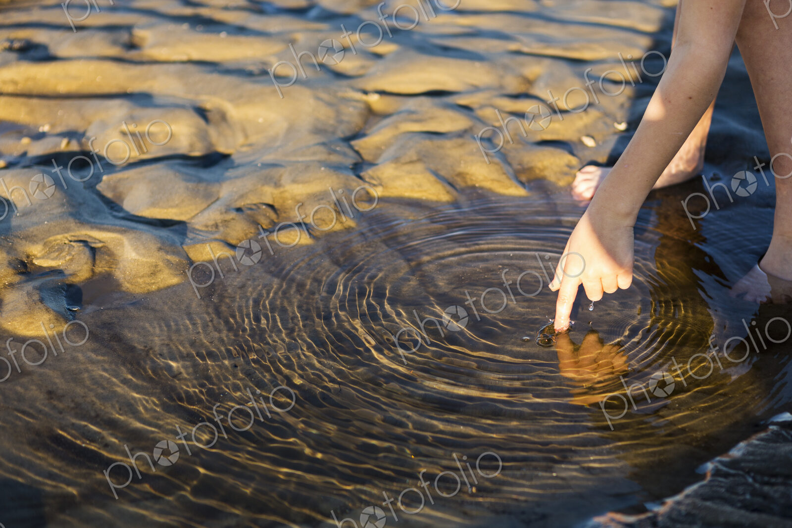 Close up of young boys finger touching water.