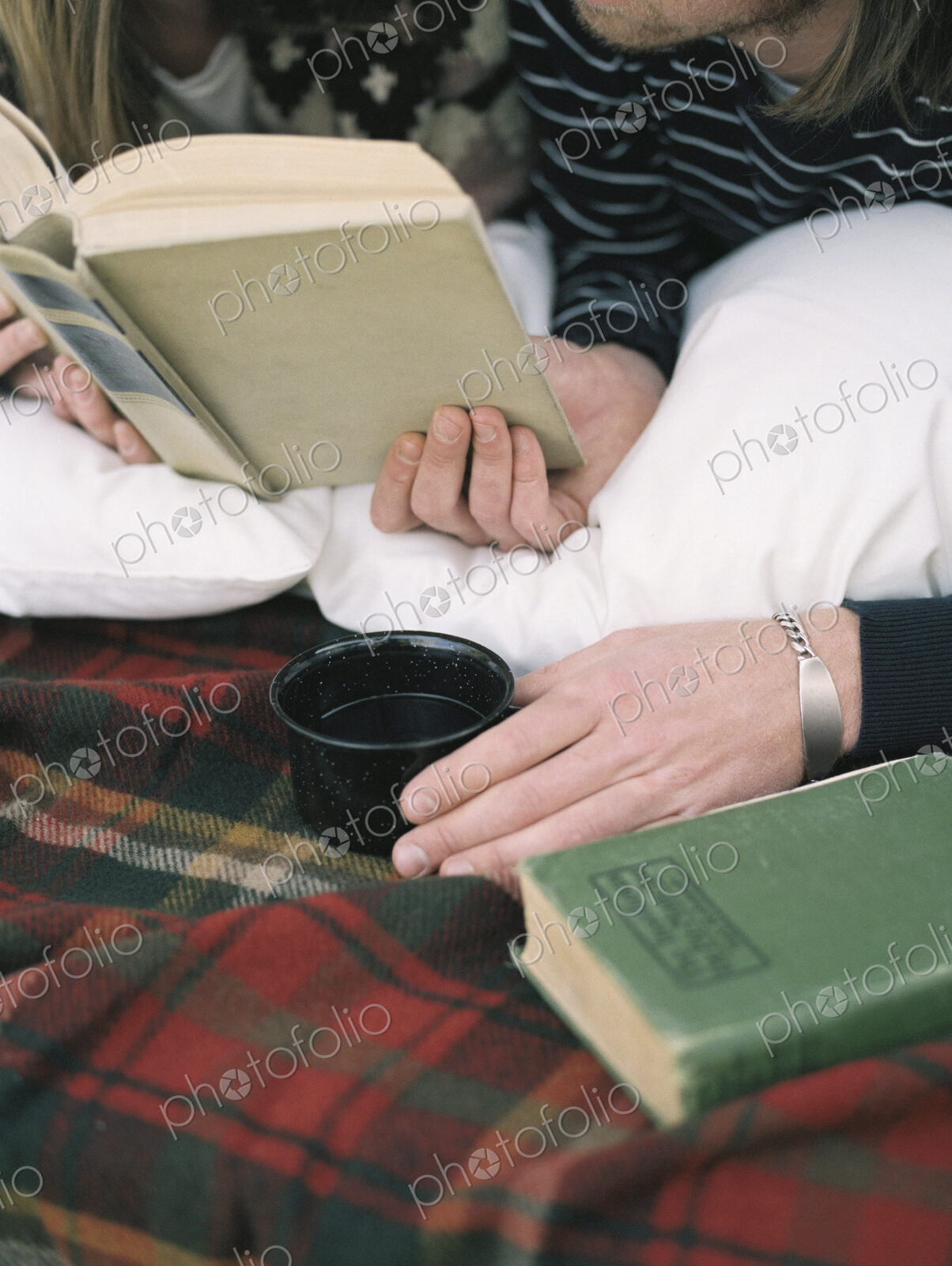 Close up of young man reading a book, holding a mug.