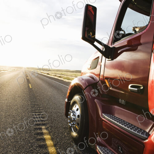 Close up side view looking forward of a commercial truck on a highway at sunset. Close up side view looking forward of a commercial truck on a highway at sunset.