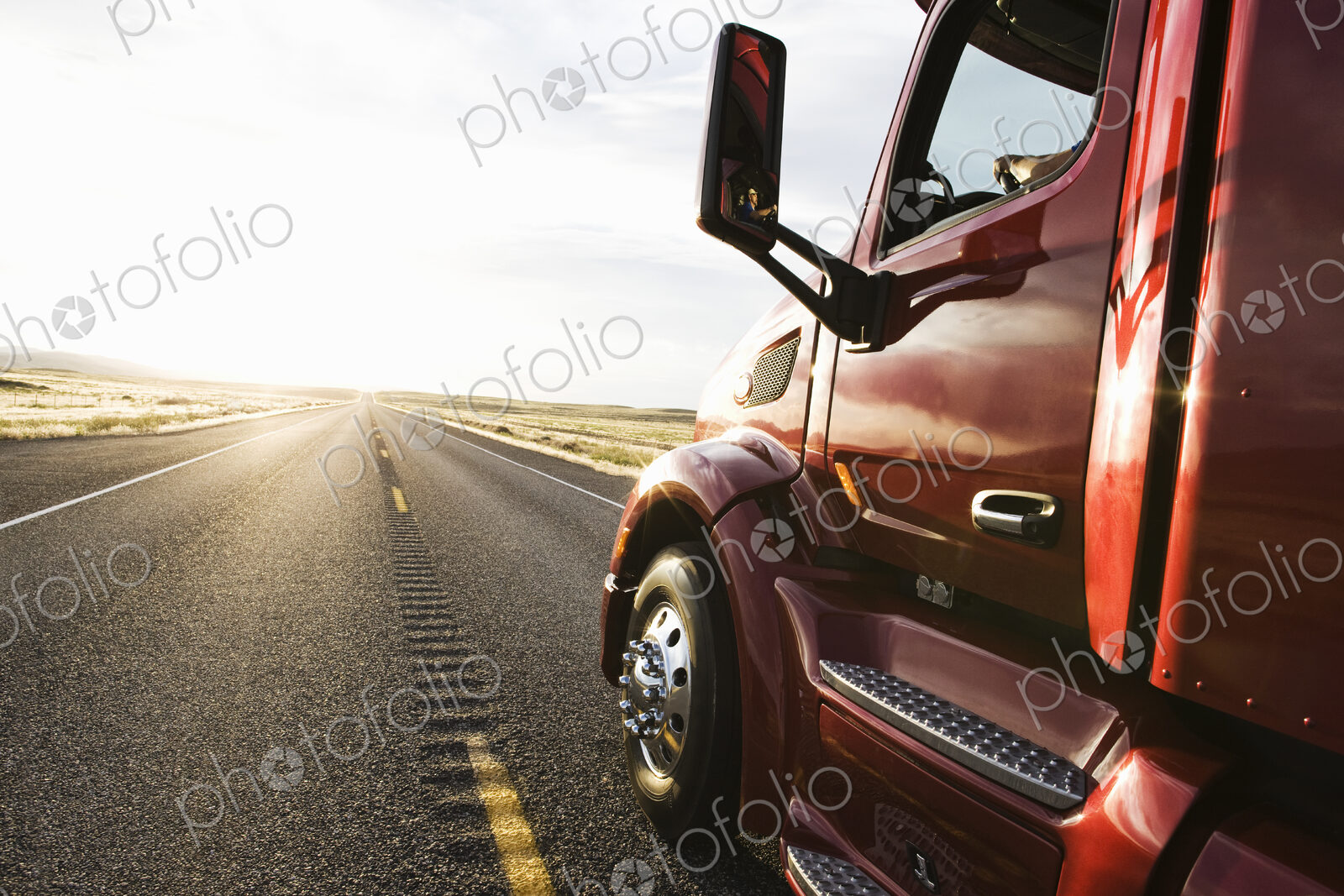 Close up side view looking forward of a commercial truck on a highway at sunset.