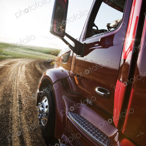 Close up side view looking forward of a commercial truck on a highway at sunset. Close up side view looking forward of a commercial truck on a highway at sunset.