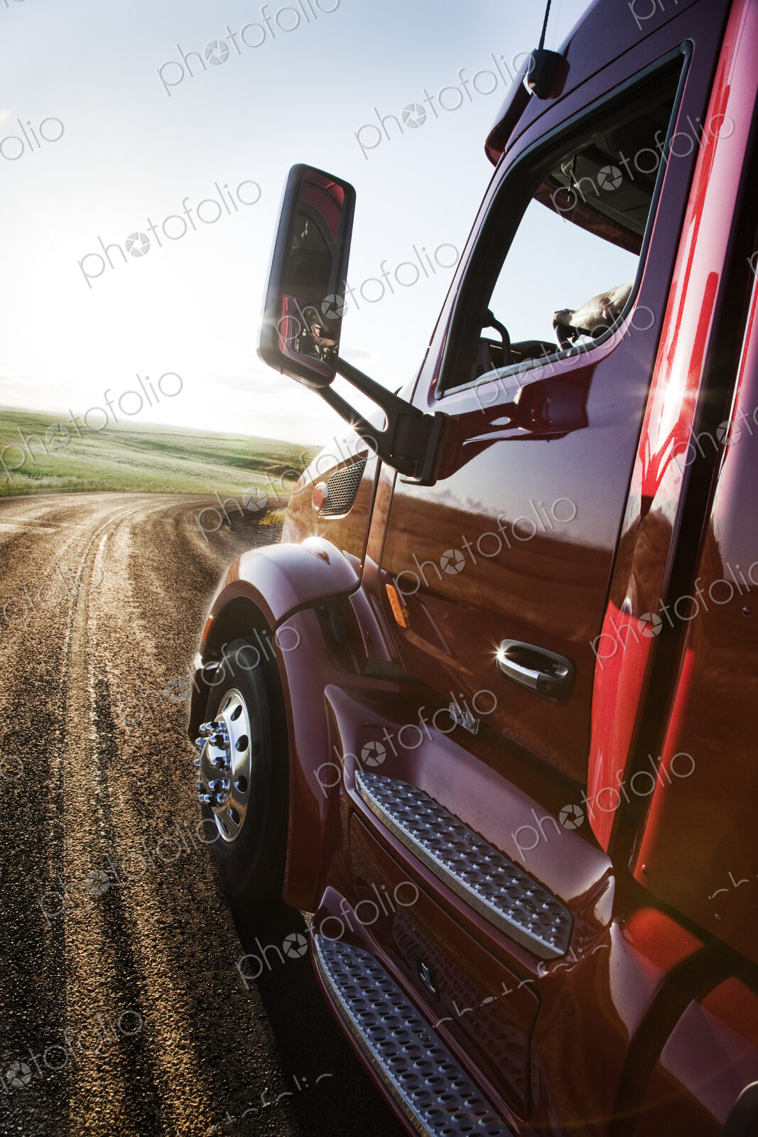 Close up side view looking forward of a commercial truck on a highway at sunset.