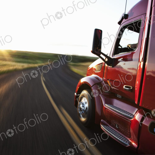 Close up side view looking forward of a commercial truck on a highway at sunset. Close up side view looking forward of a commercial truck on a highway at sunset.