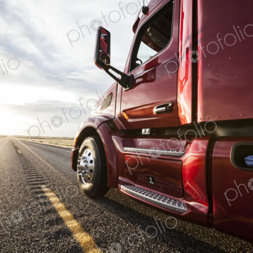 Close up side view looking forward of a commercial truck on a highway at sunset. Close up side view looking forward of a commercial truck on a highway at sunset.