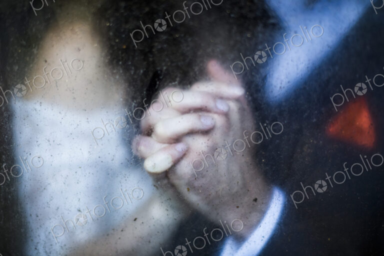 Close up through dirty window of of couple holding hands.