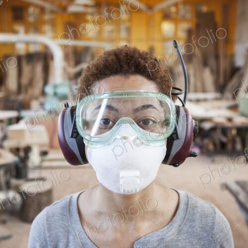 Close up view of black woman factoy worker wearing safety glasses and dust nose mask…
