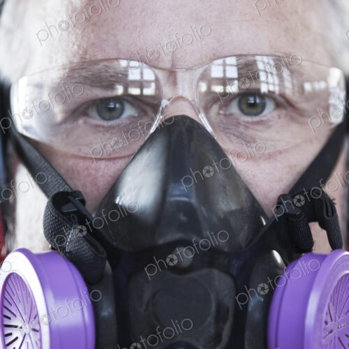Close up view of caucasian man factory worker wearing safety glasses and respirator.