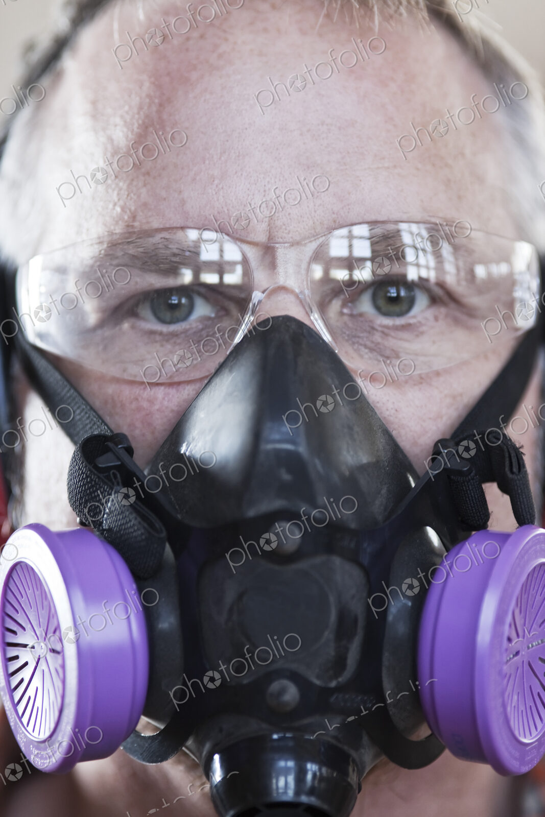 Close up view of caucasian man factory worker wearing safety glasses and respirator.