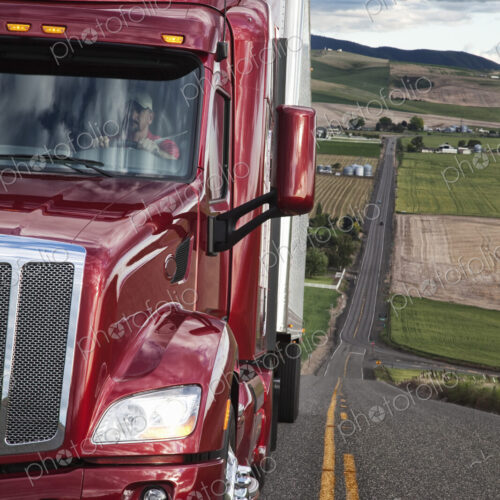 Close up view of the cab and driver of a commercial truck on the highway.