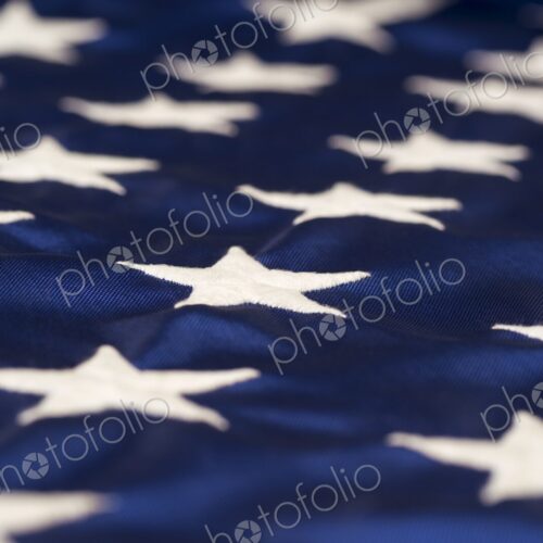 Close-up view of white embroidered stars on the blue field of the American flag -… Close-up view of white embroidered stars on the blue field of the American flag -…