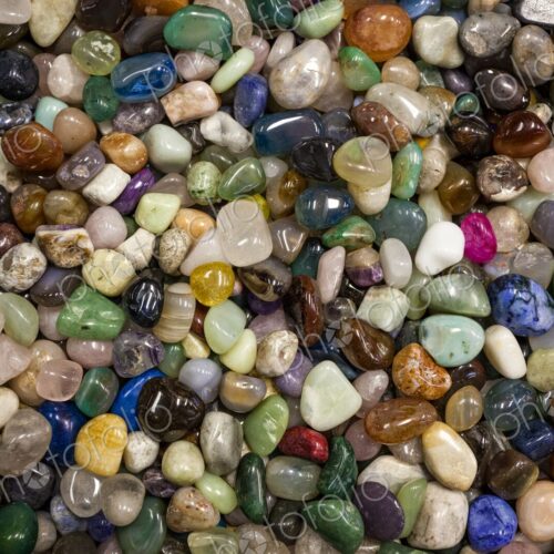 Close view of a large collection of colorful polished stones filling the frame,…