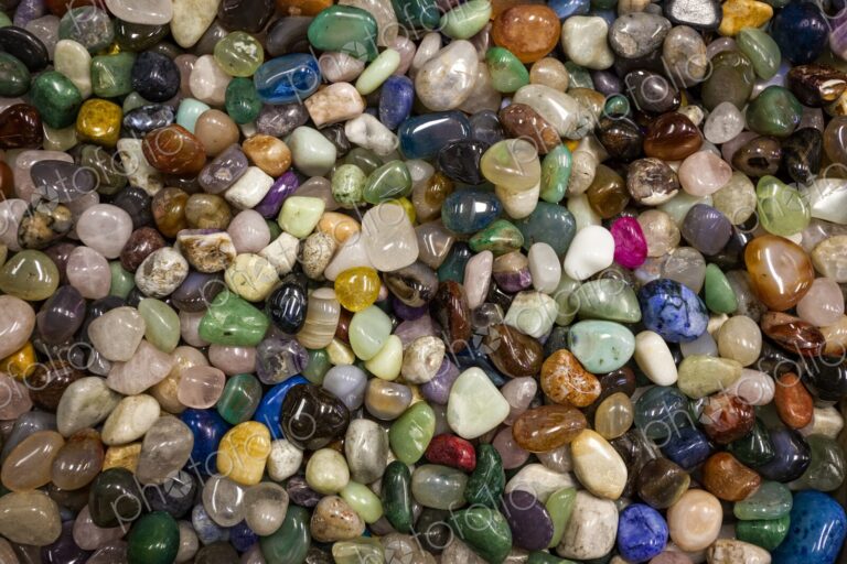 Close view of a large collection of colorful polished stones filling the frame,…