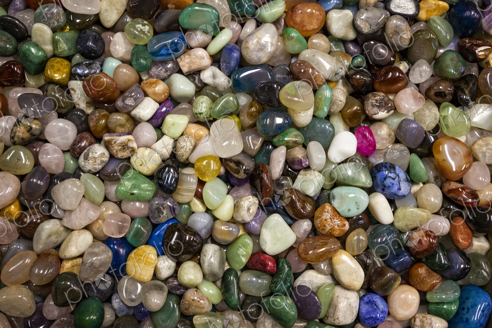 Close view of a large collection of colorful polished stones filling the frame,…