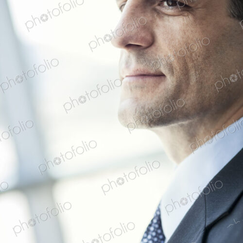 Closeup of a Caucasian businessman looking out the widow of a conference centre lobby.