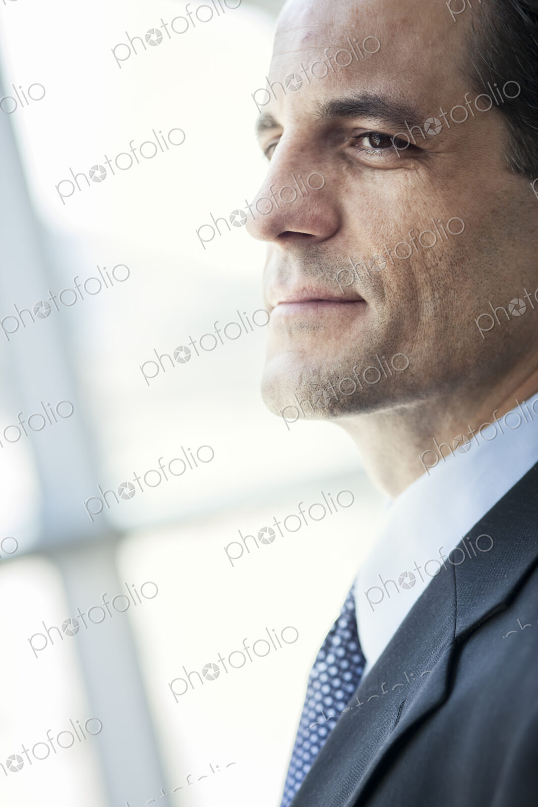 Closeup of a Caucasian businessman looking out the widow of a conference centre lobby.