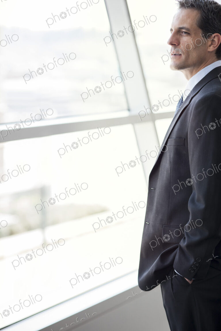 Closeup of a Caucasian businessman looking out the widow of a conference centre lobby.