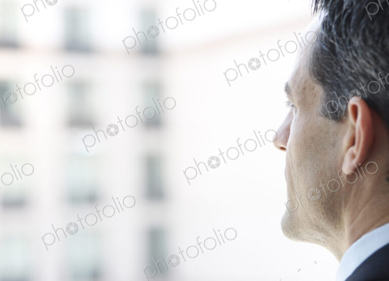 Closeup of a Caucasian businessman lookng out the widow of a conference centre lobby.