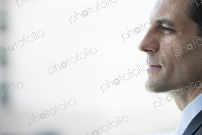 Closeup of a Caucasian businessman lookng out the widow of a conference centre lobby.