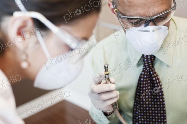 Closeup of a dentist and his assistant working on a patient in a dental office.