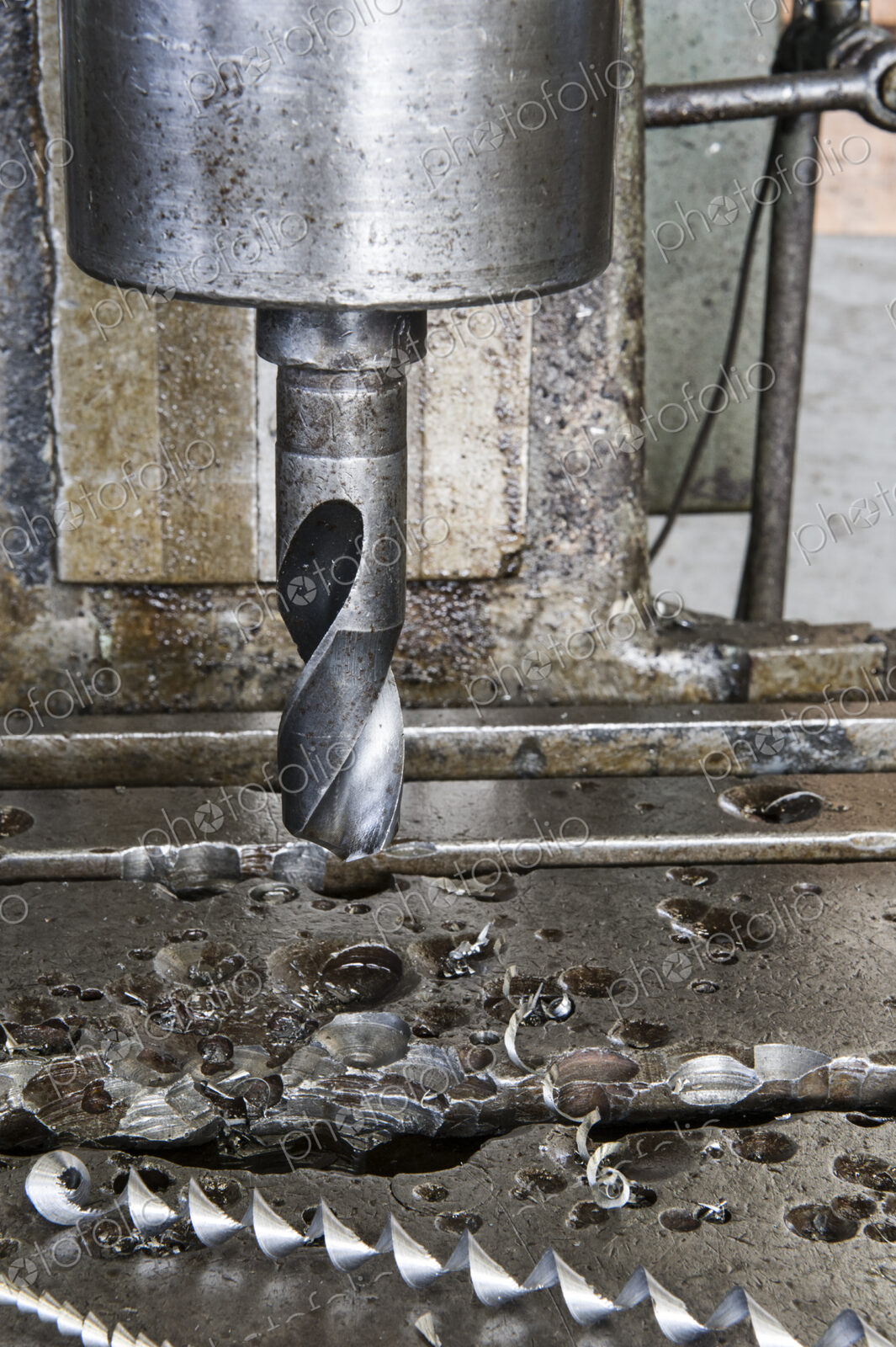 Closeup of a drill bit in a drill press in a sheet metal factory.