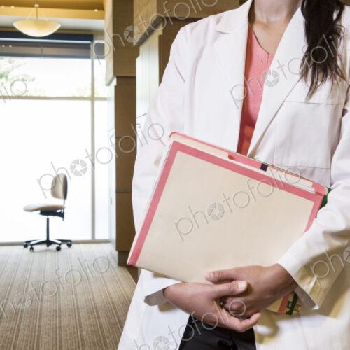 Closeup of a female dentist in her office holding file folders. Closeup of a female dentist in her office holding file folders.