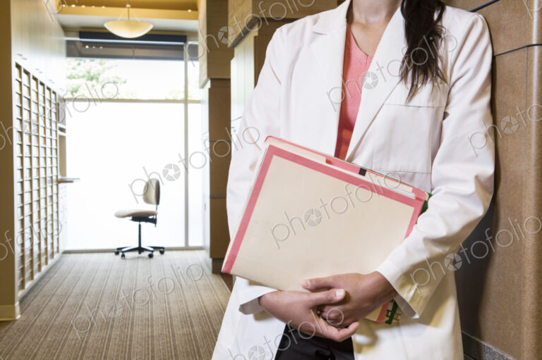 Closeup of a female dentist in her office holding file folders.
