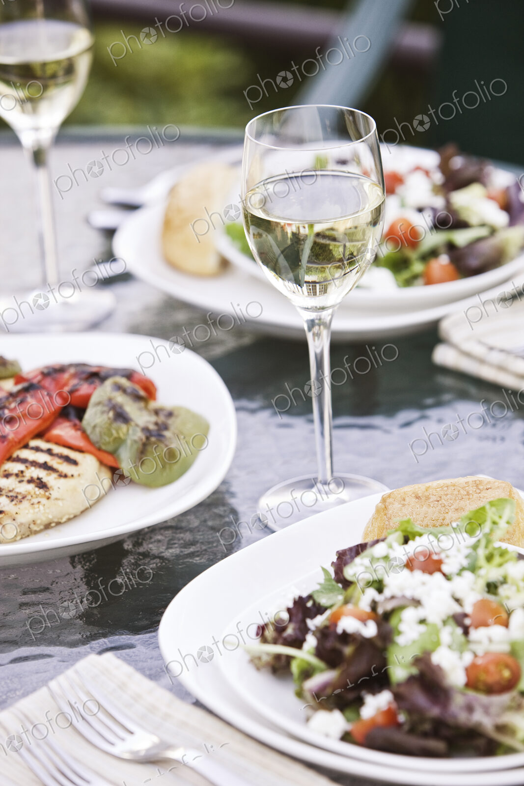 Closeup of a glass of wine and a healthy meal of salad on a table.
