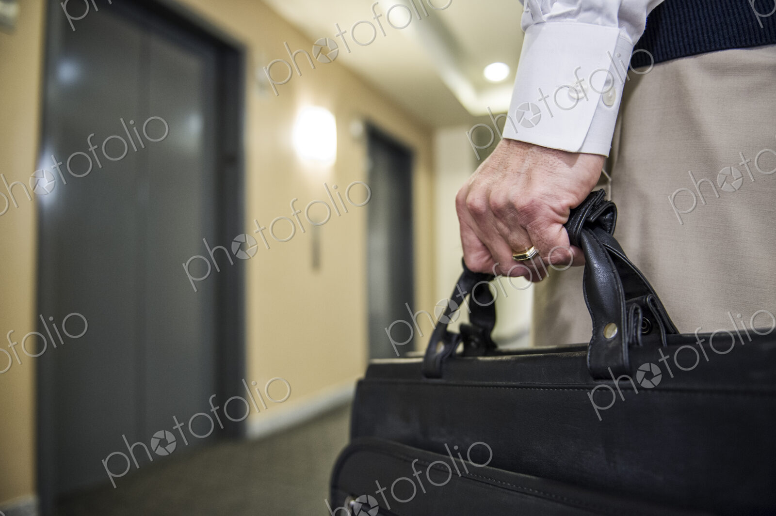 Closeup of a hand carrying a brief case in an office environment.