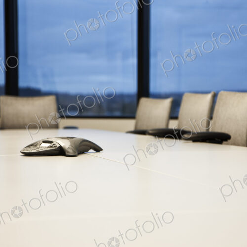 Closeup of a speaker phone on a conference table.