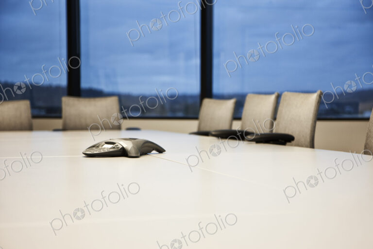 Closeup of a speaker phone on a conference table.
